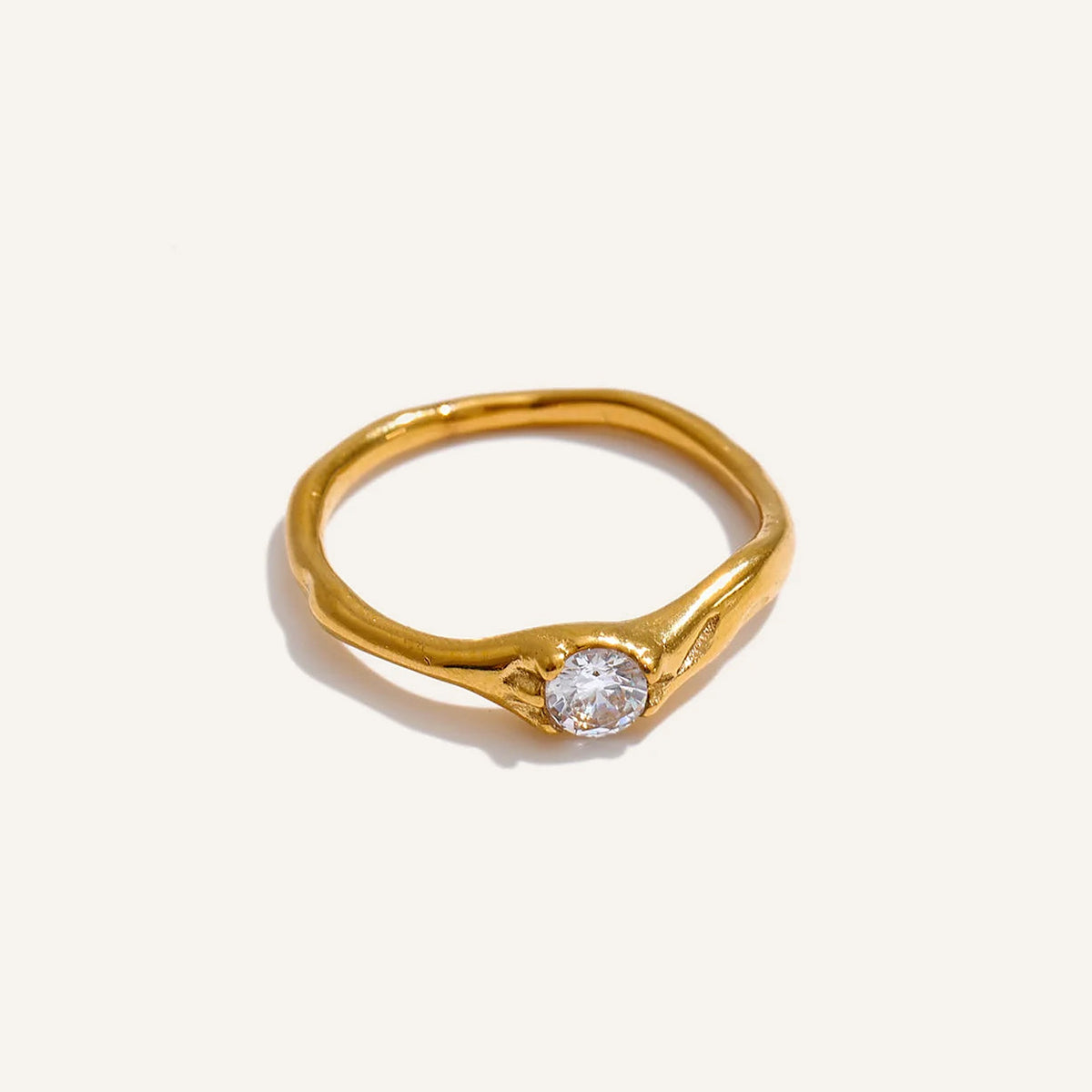 Bague solitaire ondulée avec zircon, dorée, sur fond clair – Charmhabit