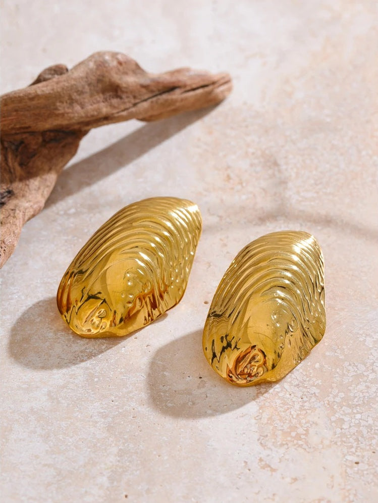 Large ribbed shell-shaped stud earrings on a light background with wood – Charmhabit