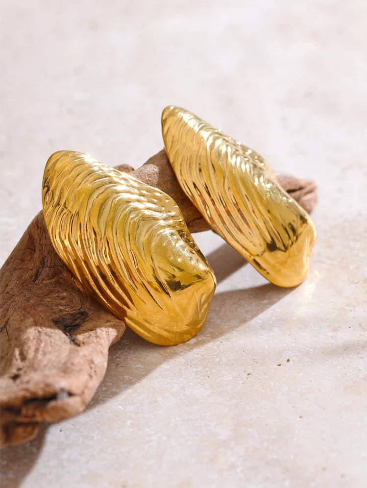 Large ribbed shell-shaped stud earrings beside driftwood – Charmhabit