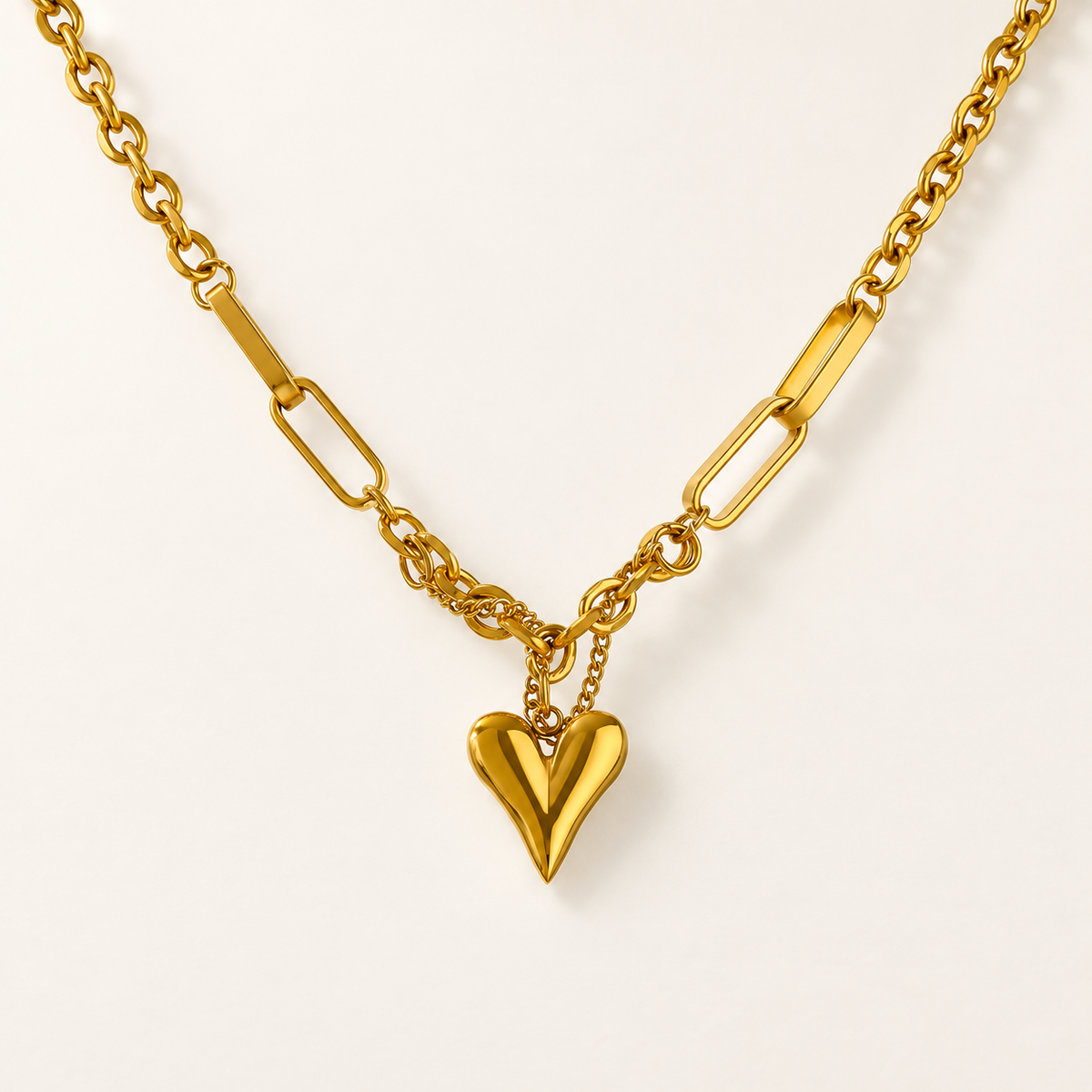 Goudkleurige ketting met hartvormige hanger op een rustige ivoorkleurige achtergrond