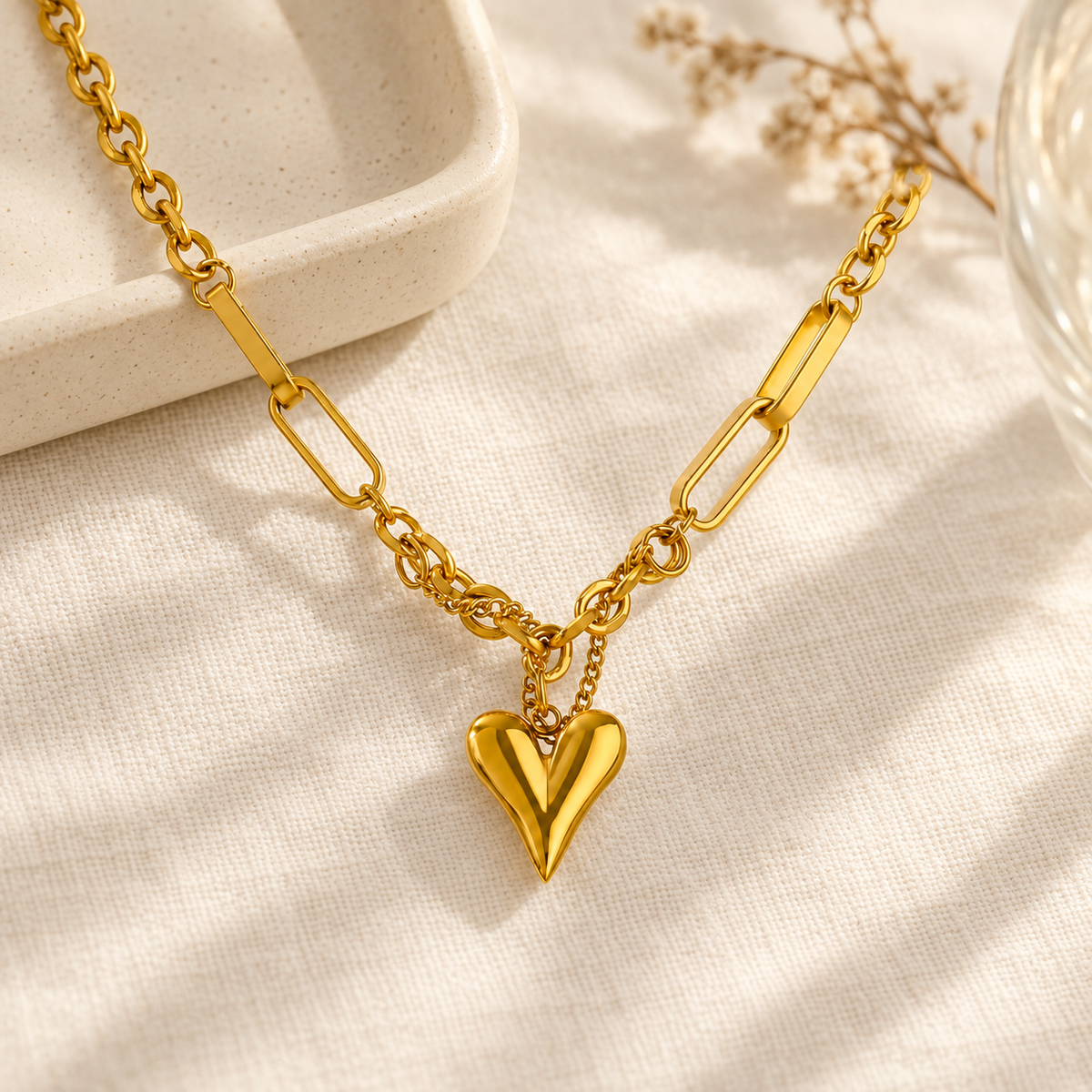Goudkleurige ketting met hartvormige hanger op licht linnen in een warme setting