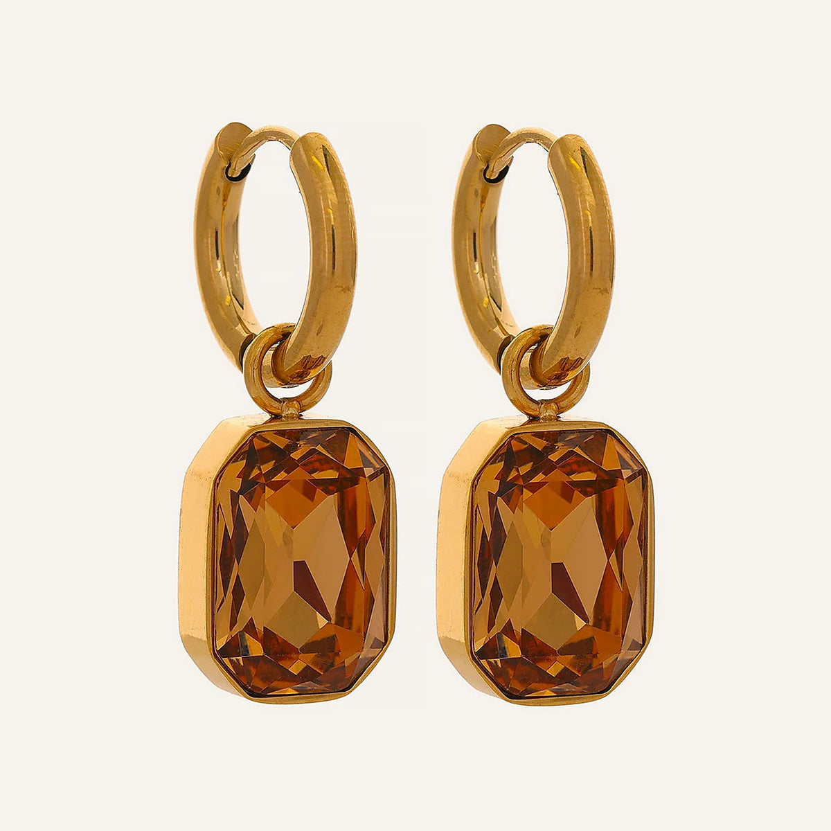 Huggie hoops with an octagonal crystal pendant in champagne, on a light background – Charmhabit