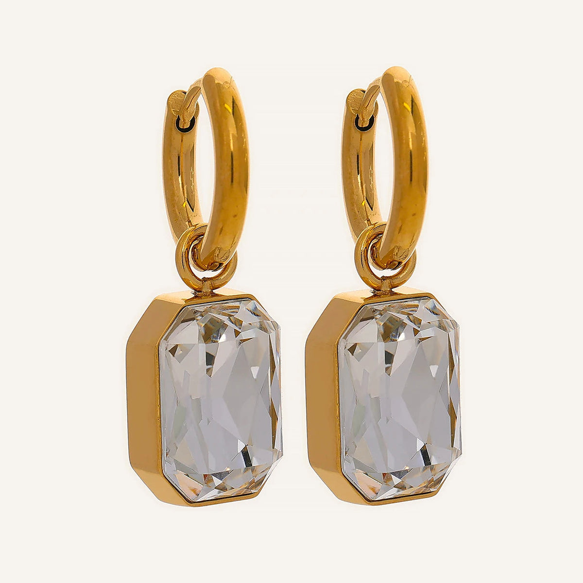Huggie hoops with an octagonal crystal pendant in a clear shade, on a light background – Charmhabit
