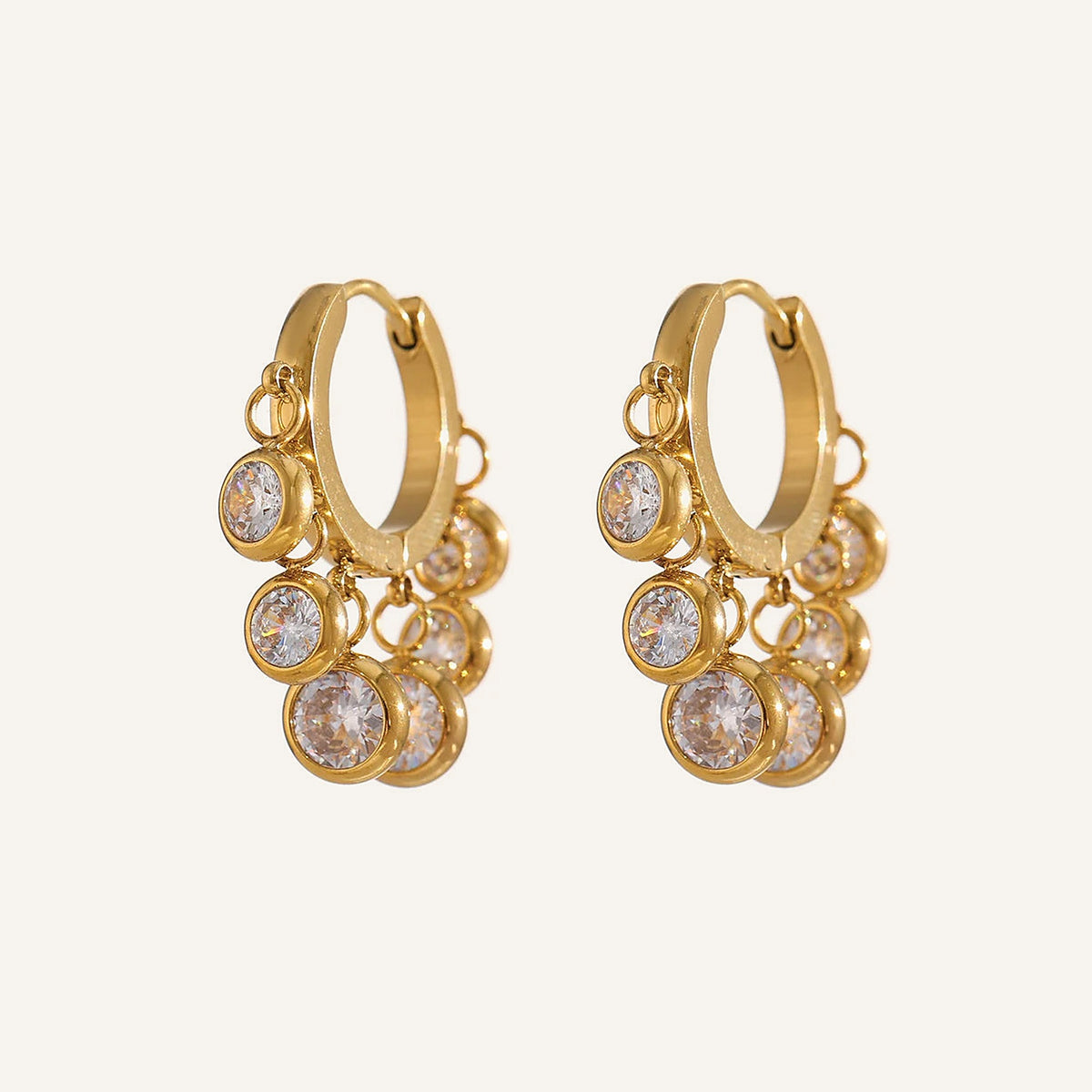 Créoles huggies avec pampilles en zircon coloré, zircons incolores, dorées, sur fond clair – Charmhabit