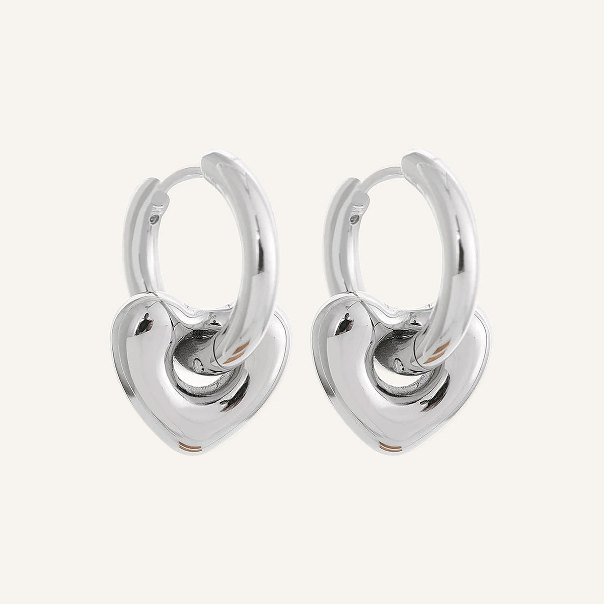 Huggie hoops with rounded heart charm, silver tone, on a light background – Charmhabit