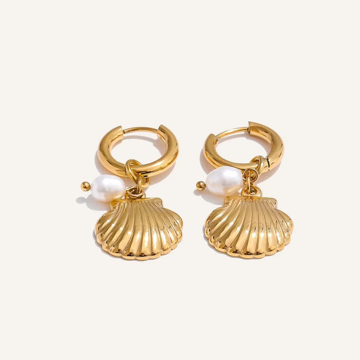 Huggie hoops with sea charm and pearl, shell, gold tone, on a light background – Charmhabit
