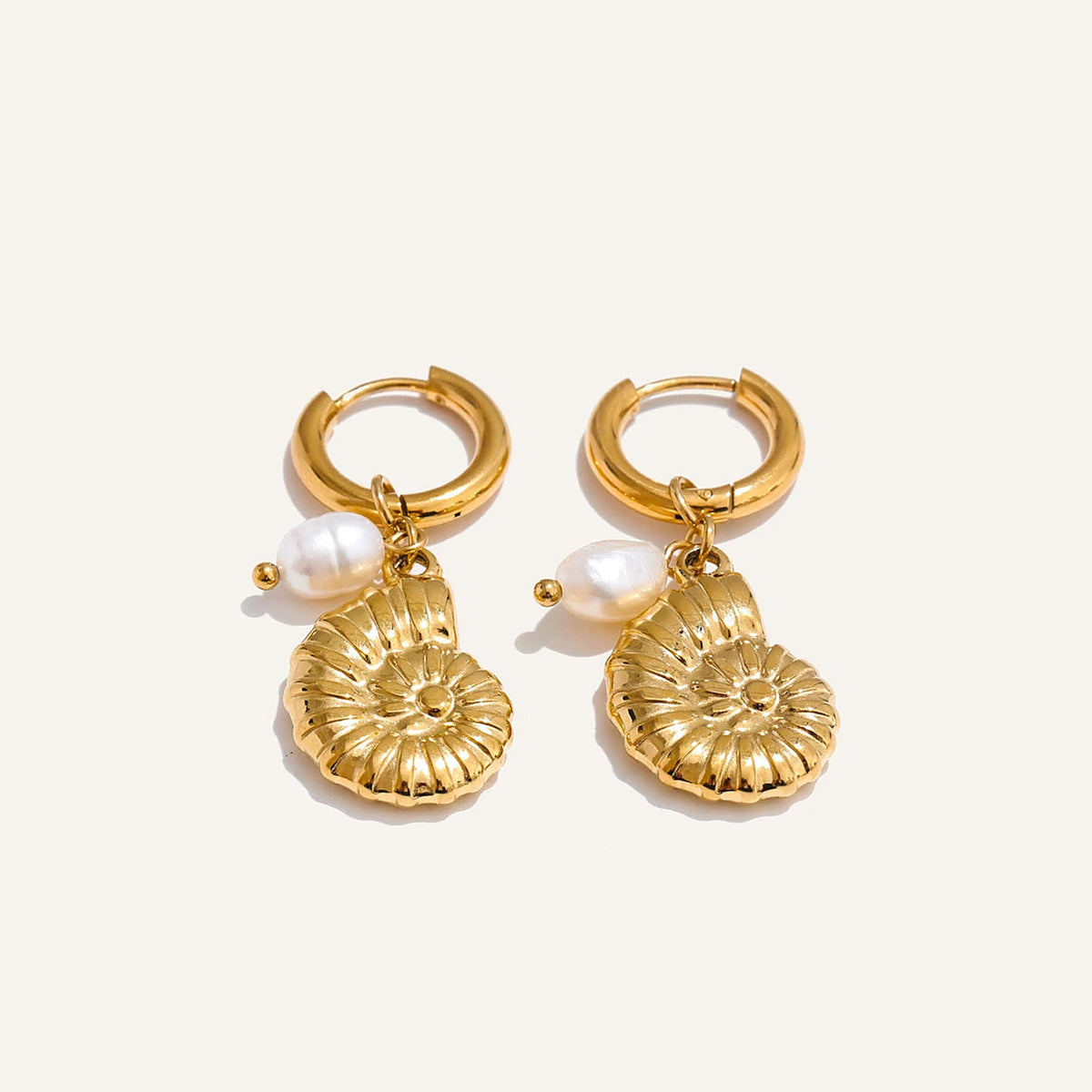 Huggie hoops with sea charm and pearl, snail shell, gold tone, on a light background – Charmhabit
