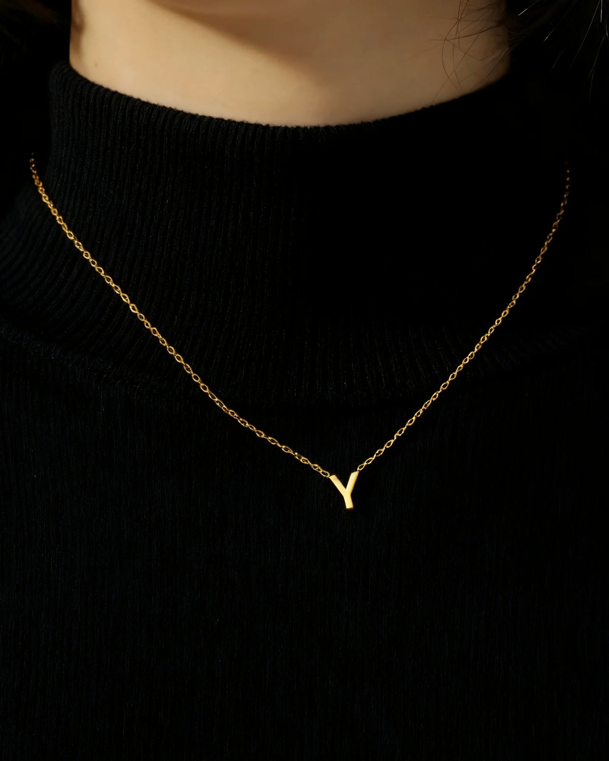 Initialenkette mit Buchstabenanhänger, goldfarben, getragen auf einem schwarzen Oberteil – Charmhabit