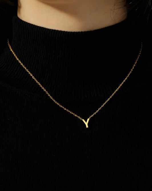 Initialenkette mit Buchstabenanhänger, goldfarben, getragen auf einem schwarzen Oberteil – Charmhabit