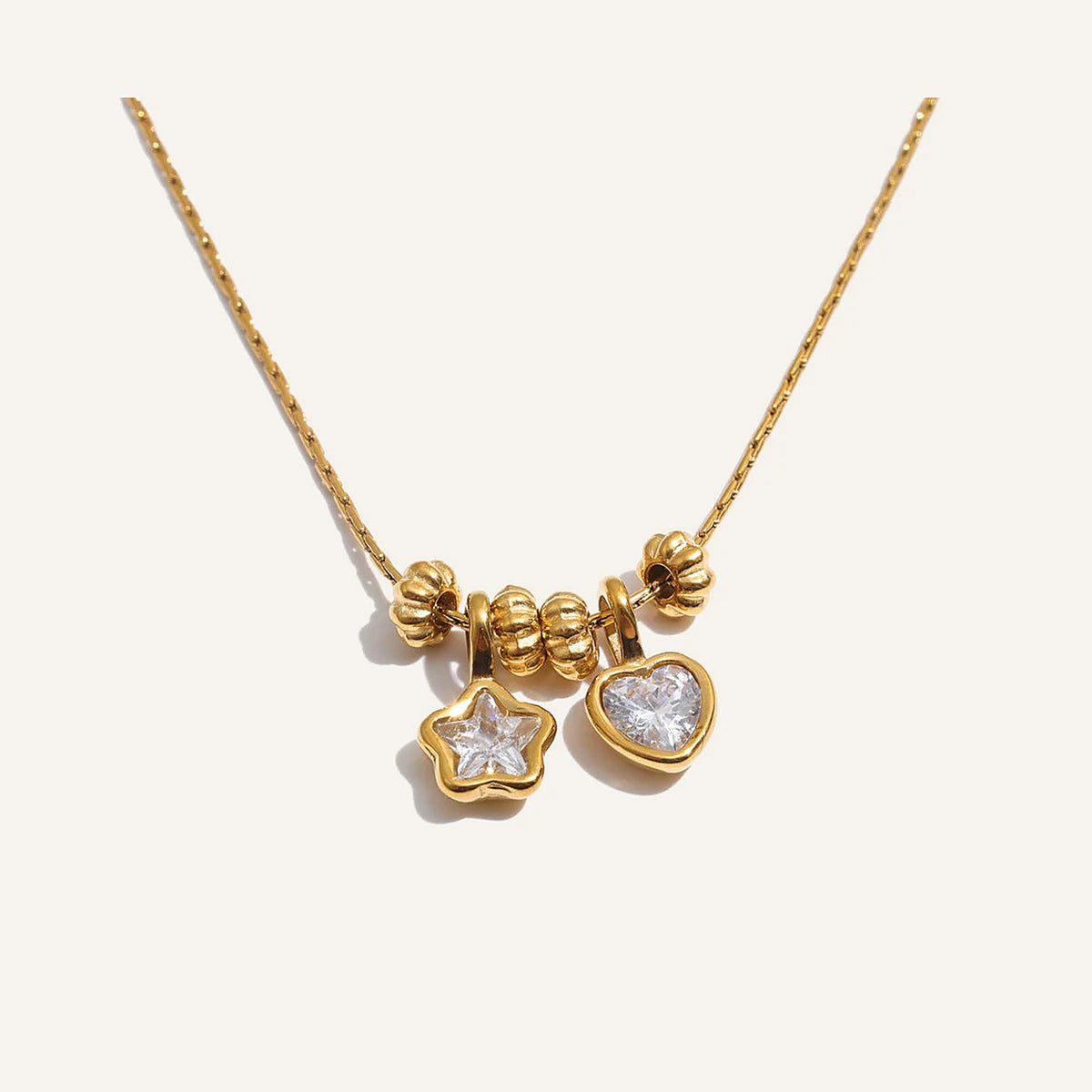 Necklace with heart and star charms, gold tone, on a light background – Charmhabit