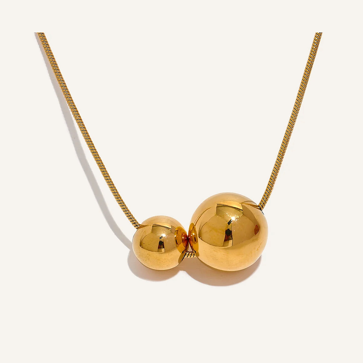 Collier à deux boules, doré, sur fond clair – Charmhabit