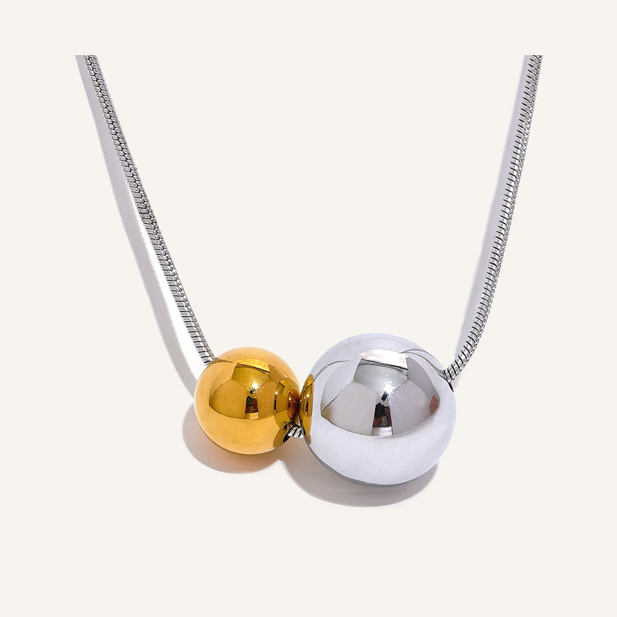 Collier à deux boules, argenté et doré, sur fond clair – Charmhabit