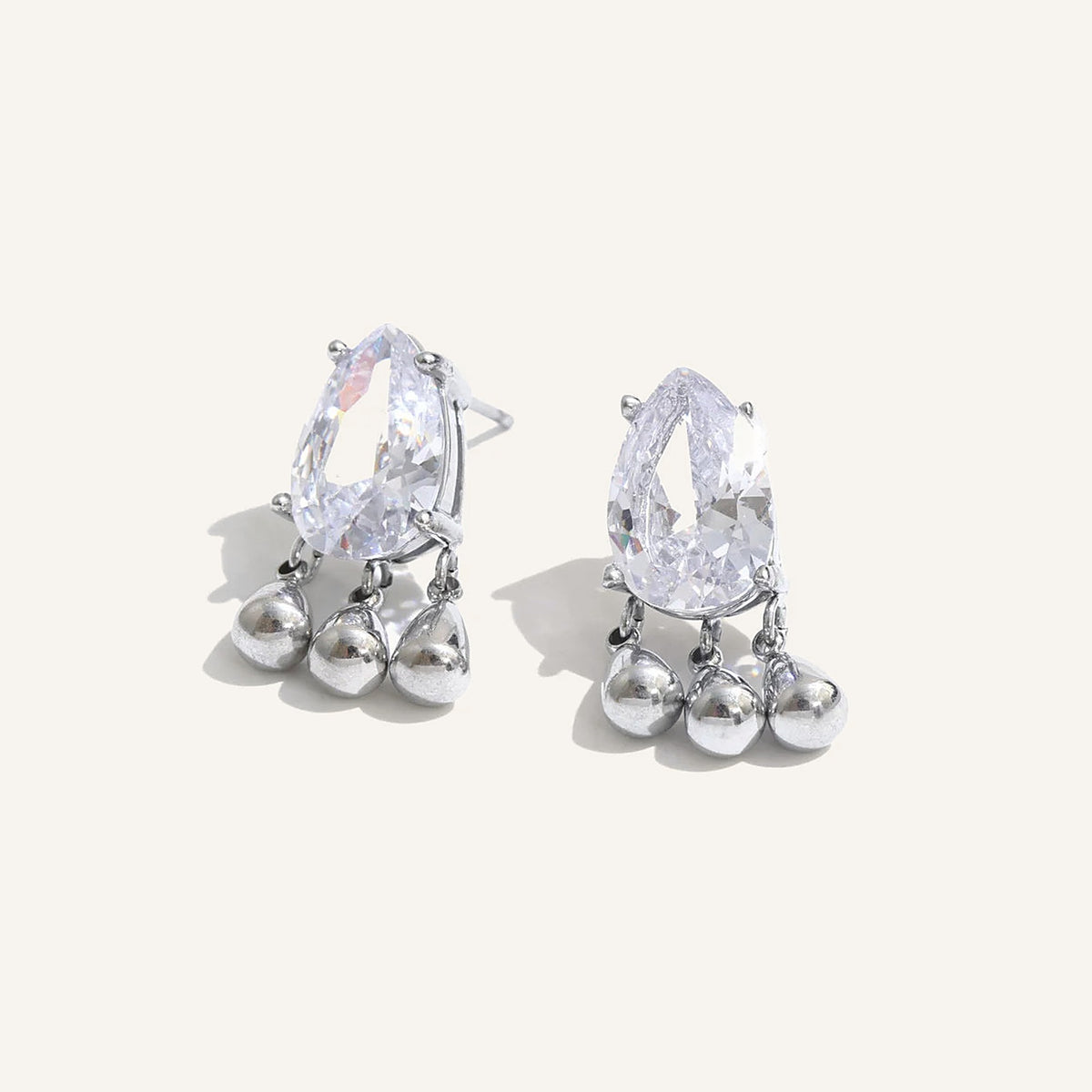 Cubic zirconia drop stud earrings with charms, silver tone, on a light background – Charmhabit