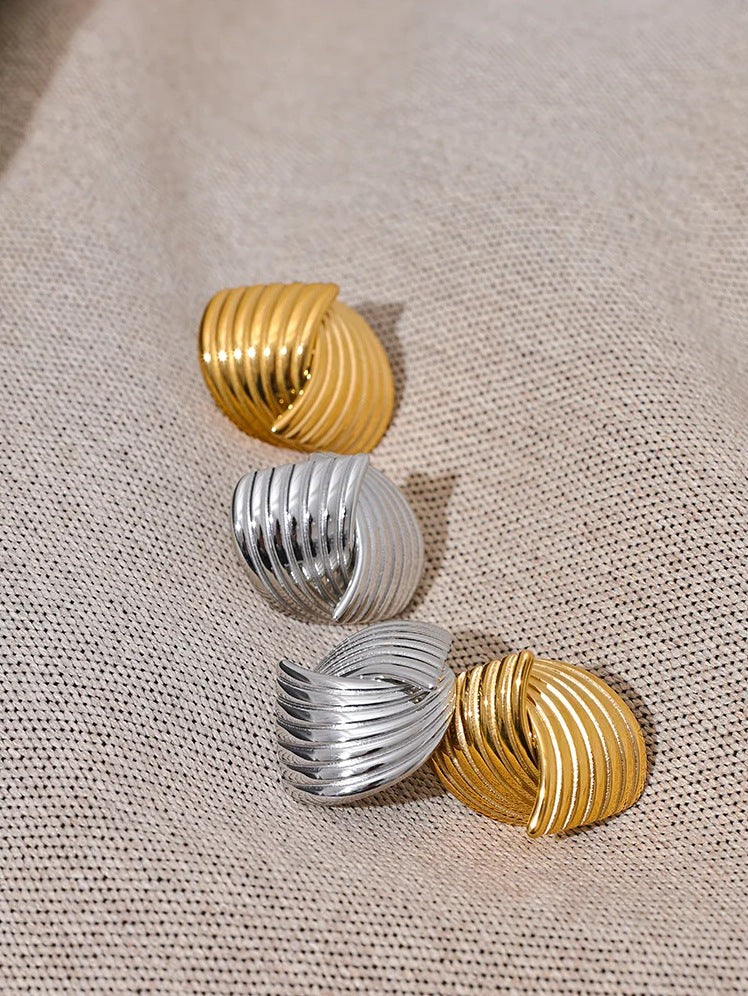 Stud earrings with ribbed loops in gold tone and silver tone on a soft surface – Charmhabit