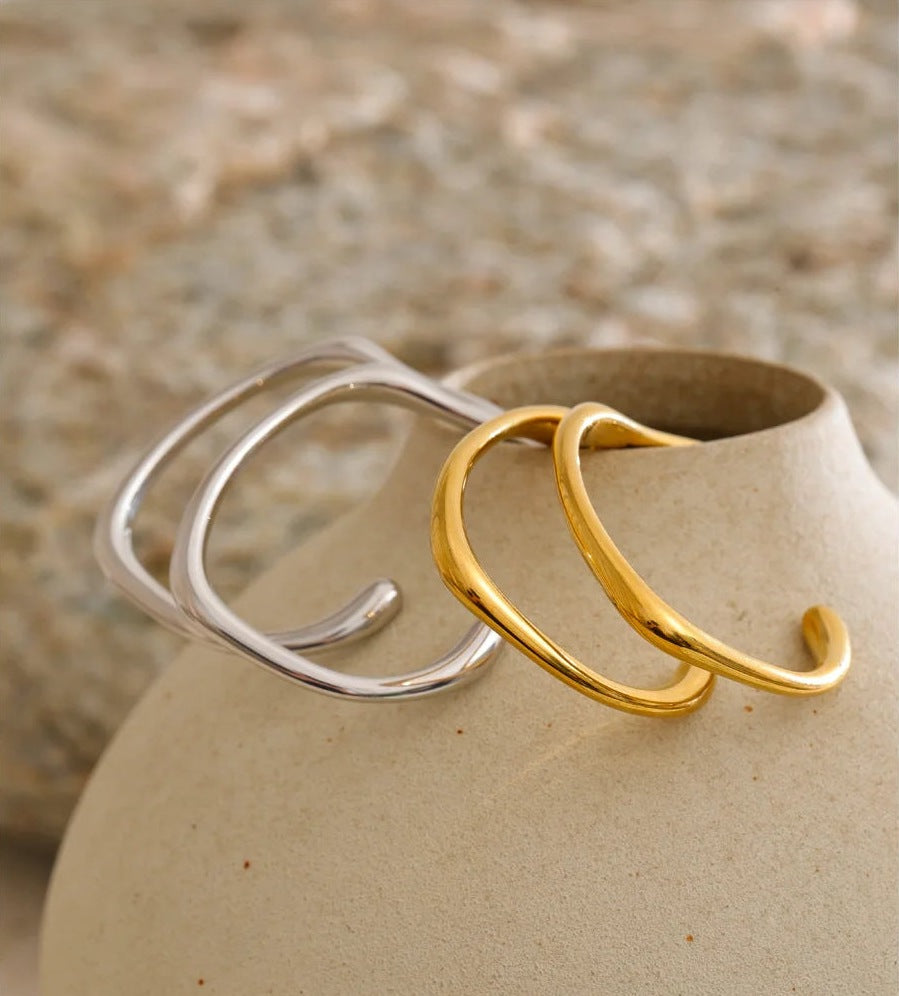 Open C-shaped earrings with a soft curve, in gold and silver tone on a vase – Charmhabit