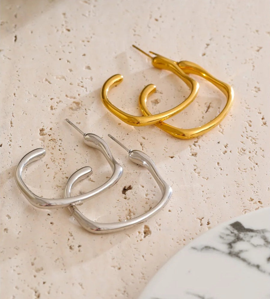 Open C-shaped earrings with a soft curve, in gold and silver tone on a light stone – Charmhabit