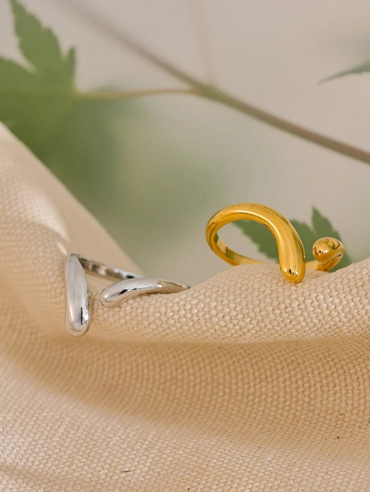 Bague ouverte ondulée, dorée et argentée, gros plan sur du lin – Charmhabit