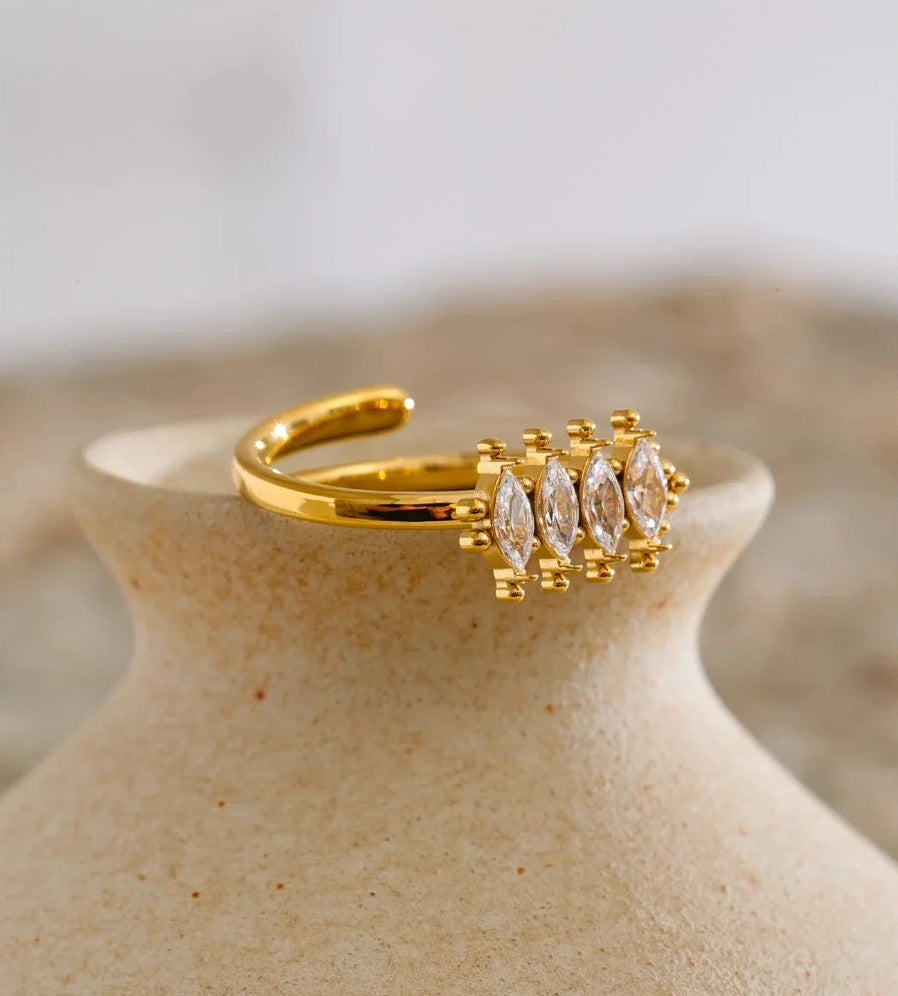 Bague ouverte avec zircons taille marquise, dorée, sur un vase en terre cuite – Charmhabit