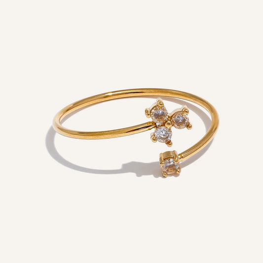 Open ring with four cubic zirconia stones in a clover setting, on a light background – Charmhabit