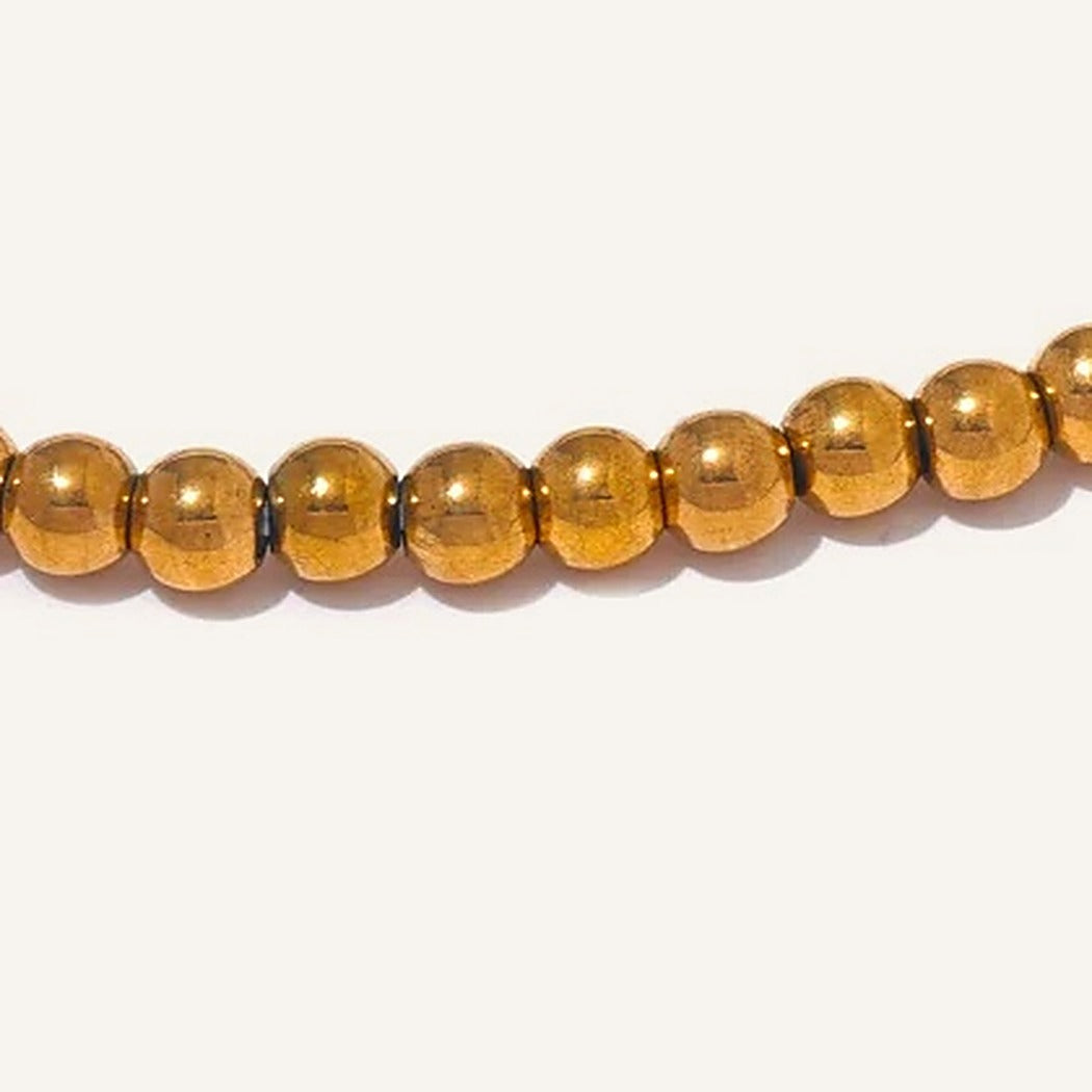 Gros plan sur le bracelet élastique avec boules lisses en acier, doré – Charmhabit