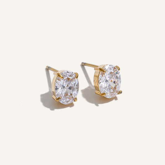 Oval cubic zirconia stud earrings in a claw setting, gold tone, on a light background – Charmhabit